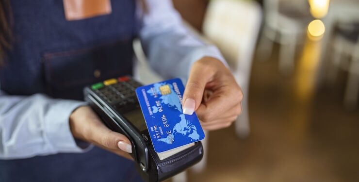 Contactless payment concept, female holding credit card near nfc technology on counter, client make transaction pay bill on terminal rfid cashier machine in restaurant store, close up view