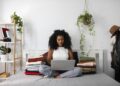 woman sitting on bed holding laptop