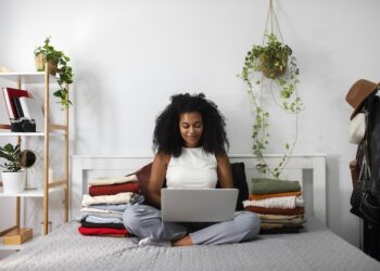 woman sitting on bed holding laptop