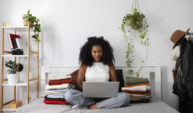woman sitting on bed holding laptop
