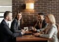 A group of business professionals having a lively discussion in a modern café setting.