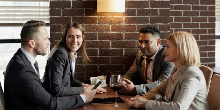 A group of business professionals having a lively discussion in a modern café setting.