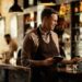 Happy barista adding an order to cash register while working in a pub.