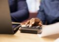 Man and woman reviewing bills and financial documents to track expenses, money management for a debt free lifestyle. Couple doing their household accounting with a calculator. Close up.